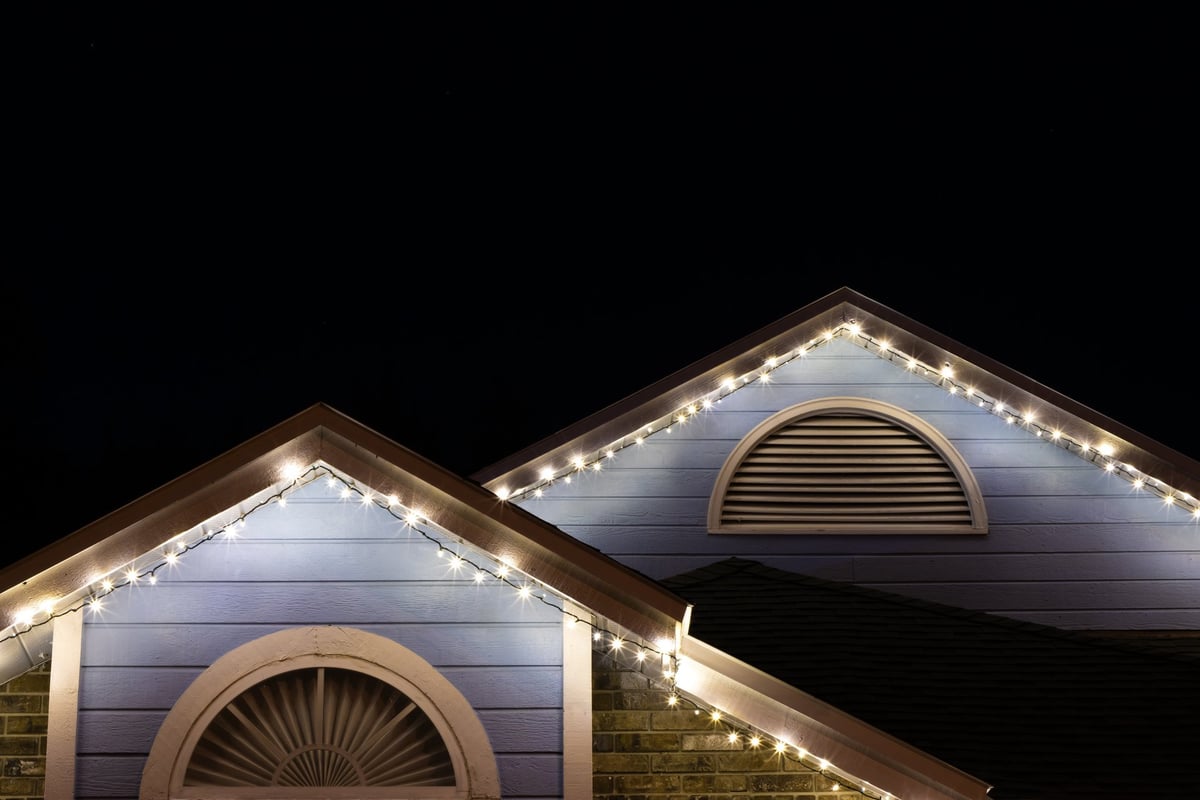 Strands of holiday lights installed along the roof of a residential house